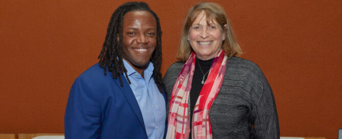 Bria stands next to Julie Greenberg, smiling, against a plain wall at the California capitol building, before testifying for a bill to support intersex rights.