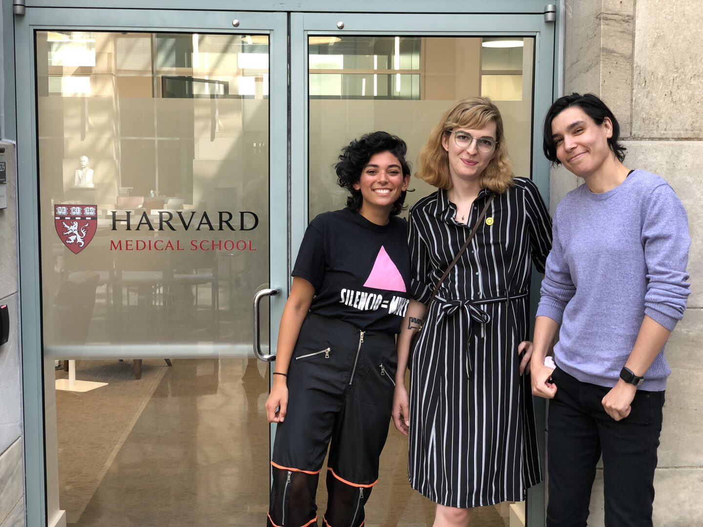 Speaking to Harvard and Boston Children's Hospital students about intersex surgery. Three advocates, Casey, Cat, and Al lean against a door to Harvard Medical School after a presentation.