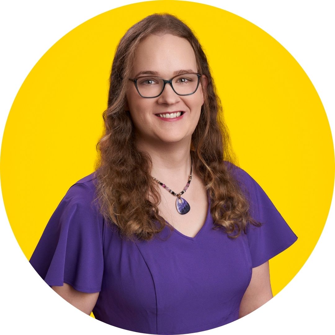 Dr Kristine Coons is a white woman with long, wavy hair and glasses wearing a purple dress and shell necklace against a yellow background,